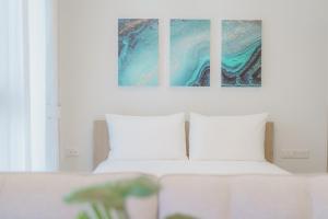 バンタオビーチにあるSkypark Apartments by Laguna Phuketのベッドルーム1室(ベッド1台付)が備わります。壁には絵画2点が飾られています。