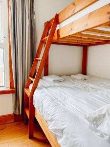 a bedroom with two bunk beds with white sheets at Reef Island Lodge in Newquay