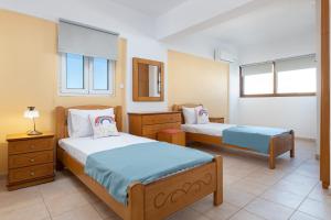 a bedroom with two beds and two tables and windows at Artoria Apartment 2 First Floor in Haraki