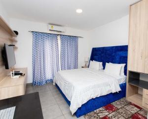 um quarto com uma cama com cortinas azuis e uma televisão em OASIS PARK RESIDENCE em East Legon