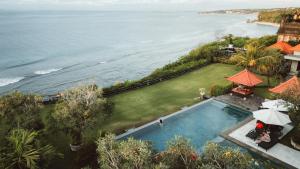 an overhead view of a swimming pool next to the ocean at Uluwatu Cottages in Uluwatu
