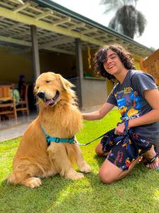 a woman is petting a dog on a leash at Pousada Vale dos Tamanduás in Olímpia