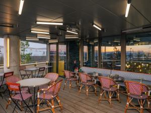 a restaurant with tables and chairs on a deck at Eklo Lyon in Vénissieux