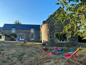 eine Gruppe von Stühlen und einem Tisch vor einem Steinhaus in der Unterkunft Maison de 4 chambres avec jardin clos a Saint Cast le Guildo a 1 km de la plage in Saint-Cast-le-Guildo