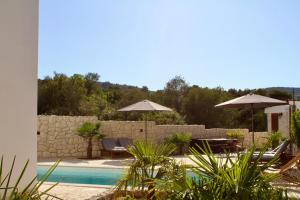 a pool with chairs and umbrellas next to a wall at Villa Bora - Ferienhaus am Meer in Slatine