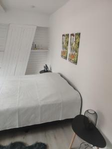 a white bedroom with a bed and a table at Het Kapittel in Ieper