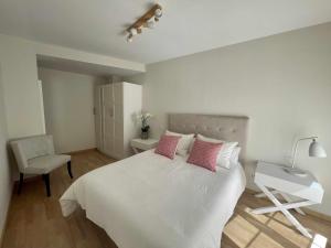 a bedroom with a white bed with pink pillows and a desk at Zabella Mercado central in Zaragoza