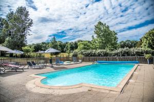 a swimming pool in a yard with chairs and a fence at Gîte Libellule au coeur de la nature in Moncoutant