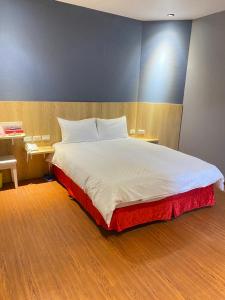 a bedroom with a large white bed and a wooden floor at The Prince Hotel in Tainan