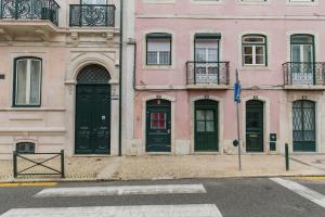 un edificio rosa con puertas negras en una calle en Secret Garden House en Lisboa