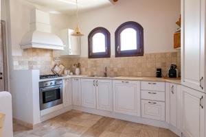 a white kitchen with white cabinets and two windows at Villa Dalia Punta Molara San Teodoro in San Teodoro