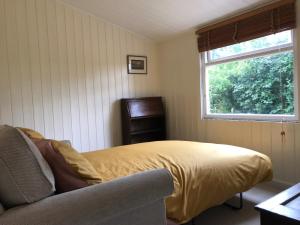 1 dormitorio con cama, ventana y silla en Adorable Hideaway with log fire and incredible views en Robertsbridge