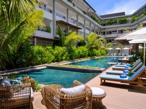 laïla, Seychelles, a Marriott Tribute Portfolio Resort في ماهي: مسبح وكراسي ومظلات بجانب مبنى