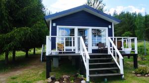 a blue tiny house with a porch and stairs at Między Lasem a Wodą in Nowe Worowo