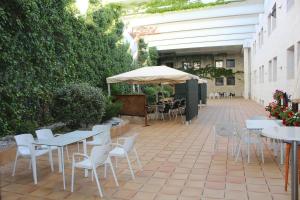 un patio con mesas, sillas y una sombrilla en Spa Hotel Ciudad de Teruel, en Teruel
