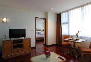 a hotel room with a television and a living room at Grand Tower Inn Rama 6 - SHA Extra Plus in Bangkok