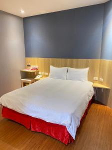 a bedroom with a large white bed with two tables at The Prince Hotel in Tainan
