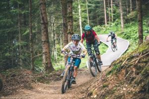 three people riding bikes on a trail in the woods at Ski In-Ski Out -Superior 2 Bedroom with Sauna at Mountain Resort Dienten am Hochkönig in Dienten am Hochkönig