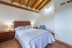 a bedroom with a white bed and a wooden ceiling at La Casonia in Anero