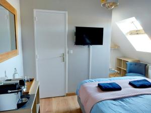 a bedroom with a bed and a tv on the wall at Chambres d'hôtes chez l'habitant - Bed & Breakfast homestay in Huisnes-sur-Mer