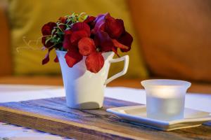 a white vase with red flowers next to a plate and a candle at Gästehaus Wolf in Pfronten