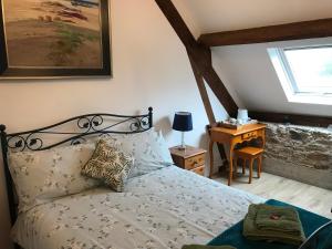 Schlafzimmer mit einem Bett und einem Schreibtisch mit einem Fenster in der Unterkunft Ferme de Noyes in Sourdeval