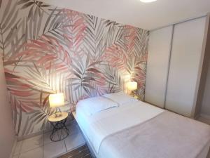 a bedroom with a bed and a tropical wallpaper at Le Voyage de Jade - Les Maisons de Madeleine in Nantes