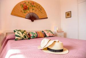a hat is sitting on a pink bed at Casa Ariel per 4, a pochi passi dalla spiaggia in Cala Gonone