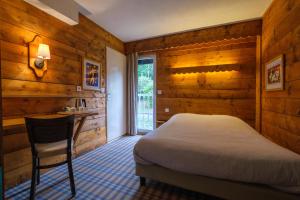 1 dormitorio con paredes de madera, 1 cama y escritorio en Cit'Hotel Le Montreal en Châlons-en-Champagne