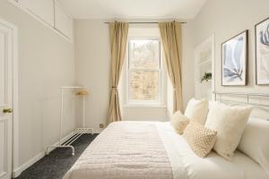 a white bedroom with a large bed and a window at The Raeburn Residence - Stockbridge in Edinburgh