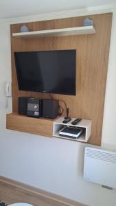 a flat screen tv sitting on a wooden shelf at Apartment With Pool Access in Temuco