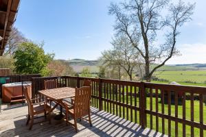 a wooden deck with a table and chairs on it at Douglas Fir Lodge with Hot tub in Cupar