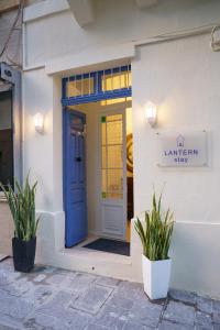 niebieskie drzwi na białym budynku z dwoma roślinami w obiekcie Lantern Stay w mieście Marsalforn