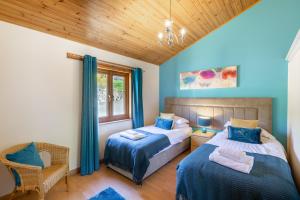 a bedroom with two beds and a chair and a window at Douglas Fir Lodge with Hot tub in Cupar