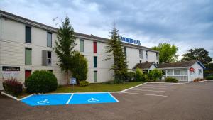 un parking en face d'un bâtiment dans l'établissement Cit'Hotel Le Montreal, à Châlons-en-Champagne