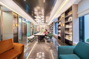 長沙市にあるAtour Hotel Changsha Dongtangの図書館のテーブルに座る女