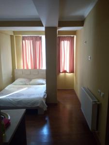 a bedroom with a bed and two windows with red curtains at vake-house in Tbilisi City