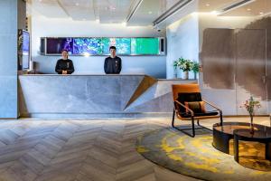 two men standing at a counter in a lobby at Atour Hotel Hongqiao Hub National Exhibition Center Shanghai in Shanghai