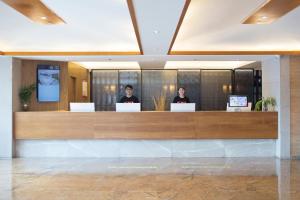 two people sitting at a reception desk in a lobby at Atour X Hotel Shenzhen Luohu Dongmen Pedestrian Street in Shenzhen