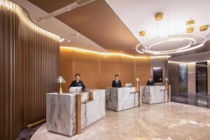 a lobby with three people sitting at desks with computers at Atour S Hotel Jinan Baotu Spring in Jinan