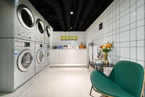 a laundry room with washing machines and a green chair at Atour Hotel Beijing Joy City Chaoyang Road in Beijing