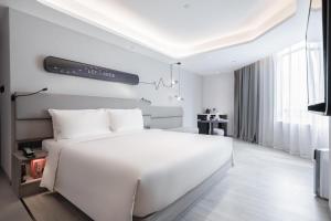 una camera bianca con un grande letto e una TV di Atour Light Hotel Guangzhou Zhujiang New Town Wuyangtun a Canton