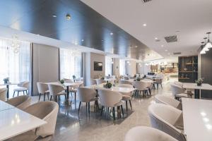 un restaurante con mesas y sillas blancas y ventanas en Atour Hotel Chongqiang Jiangbei Airport, en Chongqing