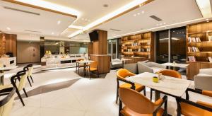 北京市にあるAtour Hotel Capital Airport Beijingのテーブルと椅子のあるレストラン、キッチンが備わります。