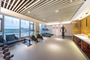 済南市にあるAtour Hotel Jinan High-tech Wanda Plaza Tiancheng Roadのトレッドミル、エクササイズ機器、窓が備わるジム