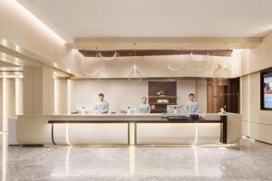 three people standing at a counter in a lobby at Atour Hotel Dalian Airport in Dalian