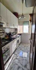 Mansouria的住宿－Maison Maurice，一间铺有大理石地板并配有白色橱柜的厨房