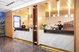 two people sitting at a counter in a lobby with their laptops at Atour Hotel Xiamen Lianban Mingfa Plaza in Xiamen