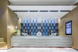 three people sitting in a lobby with their laptops at Atour Hotel Qingdao Fuzhou Road Sakura Town in Qingdao