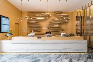 a lobby with three people sitting at a reception counter at Atour Hotel Chengdu Taikoo Li Future Center in Chengdu